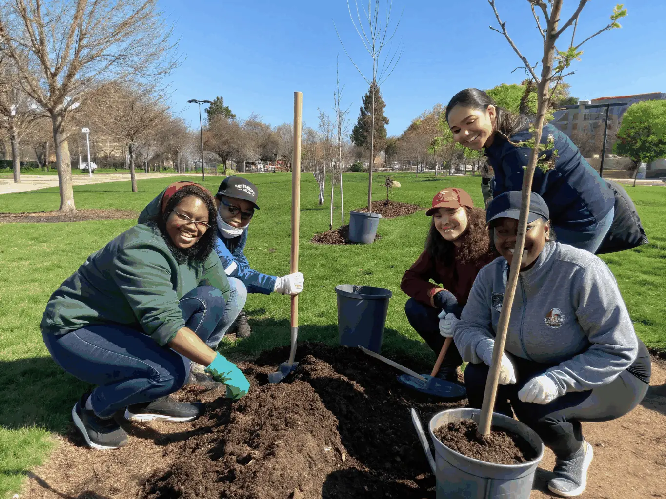 Volunteers planting trees in a local park as part of a community service initiative by COMITE DEPARTEMENTAL UFOLEP 19, highlighting the organization's commitment to community development.